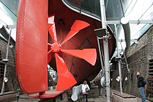 A replica of SS Great Britain's first propeller. A four-bladed model replaced the original in 1845. The ship was originally designed to have paddles, but plans changed after screw propellers were shown to be much more efficient. Great Britain propeller and rudder wideshot.jpg