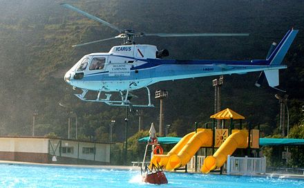 A helicopter dips its bucket into a pool before dropping the water on a wildfire close to Naples, Italy.
