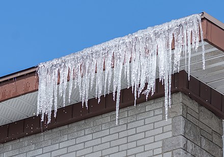 Ice stalactites on the gutter of a house