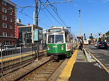 Ein Stadtbahnzug an einer Oberflächenstation im Mittel einer städtischen Straße