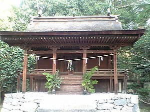 Small wooden building with a curved roof and stairs leading to a platform surrounding the building.