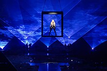 Madonna with the portal frame, designed to act like a "time machine". Some critics have highlighted her career and legacy through the retrospective tour. Madonna Celebration Tour (53334315668).jpg