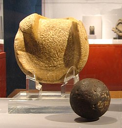A solid rubber ball used (or similar to those used) in the Mesoamerican ballgame, 300 BCE to 250 CE, Kaminaljuyu. The ball is 3 inches (almost 8 cm) in diameter, a size that suggests it was used to play a handball game. Behind the ball is a manopla, or handstone, which was used to strike the ball, 900 BCE to 250 CE, also from Kaminaljuyu. Mesoamerica - manopla and ball.jpg