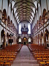 Photo de l’intérieur d'une église à voûte nervurée, dont les bas-côtés sont surmontés d'une tribune.