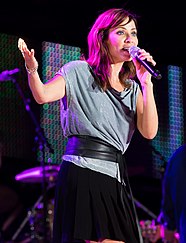 Natalie Imbruglia singt in ein schwarzes Mikrofon, das sie in der linken Hand hält. Sie trägt ein graues Oberteil, ein breites schwarzes Band um den Bauch, einen schwarzen Rock, zwei silberne Armbänder am rechten Handgelenk, einen silbernen Ring am rechten Mittelfinger sowie eine kleine schwarze Rosen-Tätowierung unter dem linken Handgelenk. Auf der Bühne hinter ihr sind der Rücken einer anderen Person, mehrere schwarze Mikrofonstangen und ein Drumset zu sehen.