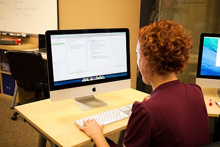 Person with desktop on desk writing java code