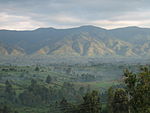 A panoramic view of a slightly foggy plain, with mountains filling the background.