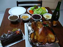 A roast turkey surrounded by a Christmas log cake, gravy, sparkling apple cider and vegetables Turkeyset.JPG