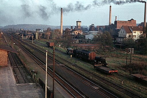 Messel in den 1950er Jahren: Blick südostwärts über den Bahnhof in Richtung Grube Messel mit den Schornsteinen des Paraffin- und Mineralölwerks Messel