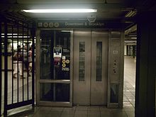 An elevator from the mezzanine to the southbound Broadway Line platform. It has a glass-and-metal enclosure and signage indicating that it leads to the "N", "Q", and "R" trains.