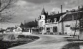 Photographie en noir et blanc d'une route longeant une ancienne commune.