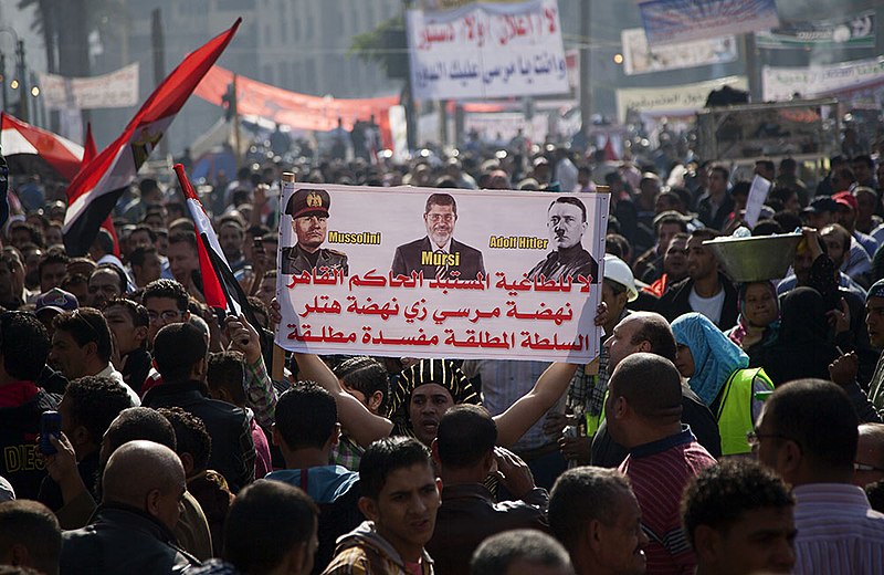 File:A protester on Tahrir Square holds up a poster comparing Morsi to former fascist leaders Mussolini and Hitler - 30-Nov-2012.jpg