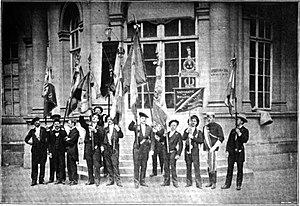 Black and white photo of a group of about 12 university students with flags.