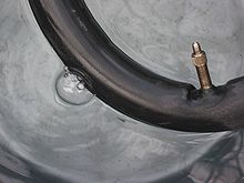 A bicycle inner tube with valve stem undergoing a leak test in water Fietband lek zoeken.jpg