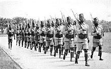 Fotografia unei coloane de soldați africani cu puști