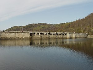 The dam with the overflows and the reservoir