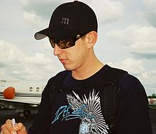 Man in his early twenties, wearing a black baseball cap and sunglasses.