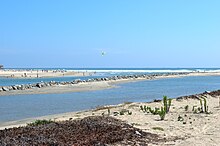 Zwischen steinernen Stegen fließt ein Fluss ins Meer