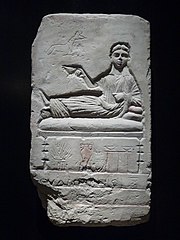 stela of Eudaimonis reclining on a couch with the god Anubis (jackal)