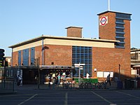A brown-bricked building with a rectangular, dark blue sign reading "TURNPIKE LANE STATION" in white letters all under a blue sky
