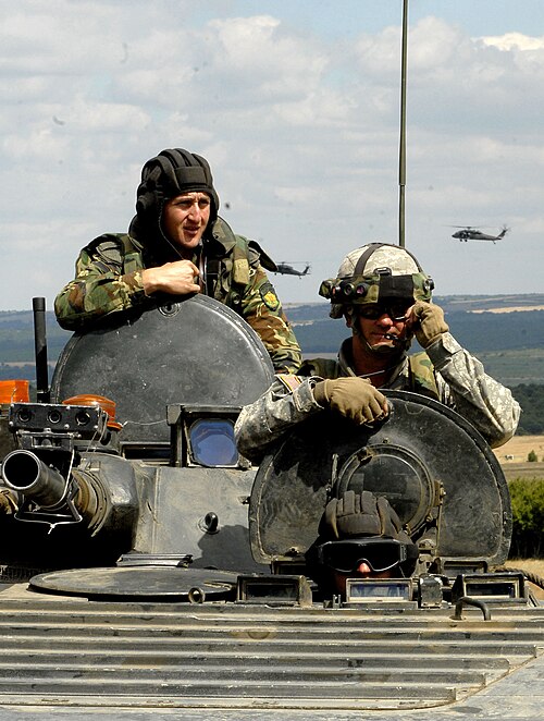 Two Bulgarian Army soldiers man the driver's and gunner's stations, while a US Army soldier occupies the commander's position of a Bulgarian BMP-1 IFV