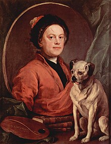 A man wearing a red robe and a black hat in a mirror. A small yellow dog with a black nose and ears stands beside the mirror.