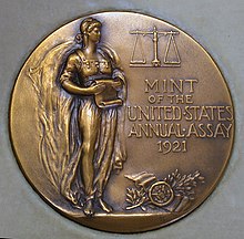 Medalha representando uma mulher, de pé, um pergaminho na mão.