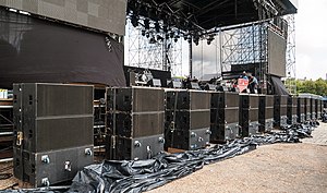 A row of subwoofer cabinets in front of the stage of a rock concert. One enclosure out of every stack of three is turned backward to make a cardioid output pattern. Caissons grave DSC 5563EC.jpg