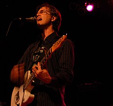 A picture of a man singing and playing a guitar