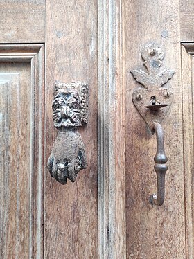 Old door handle with a door knocker next to it, on the doorway of a house in Cannelle, Corsica.