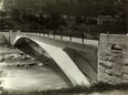 Schwarz-Weiss-Foto der flach-geschwungenen Tavanasa-Brücke vom linken Brückenkopf aus
