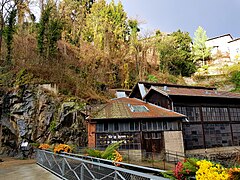 Fotografia dell'ingresso principale della fabbrica con la scogliera rocciosa sopra.