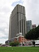 Ground-level view of 50-storey box-like building with dark, receded windows and cut-off, diagonal corners