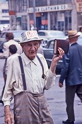 Street preacher in Los Angeles, California, 1972 Man holding Bible and sporting Jesus Saves sign on his hat.jpg