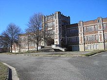 Photo of a two-story brick school building with boarded up windows.