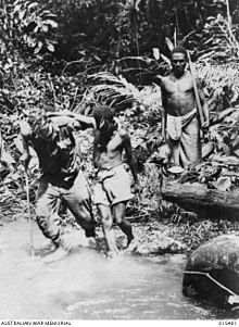 A Papuan assists Private Jerry Cronin to cross a creek after Cronin had been wounded in a clash against the Japanese. Mount Tambu fighting 4116758.jpg