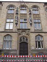 Portal mit den Heiligenstatuen; rechts der hl. Ludger mit seinem Attribut, der Gans; links der hl. Bonifatius mit Buch und Axt; Bildhauer: Franz Ewertz