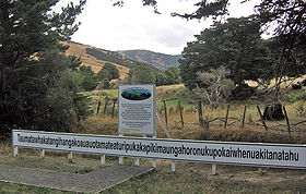 Vue du panneau au départ du sentier menant à la colline visible au dernier plan.