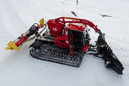 A snow groomer for alpine slopes with plow, a surface finishing attachment for ski slopes, and a cable winch for grooming steep slopes