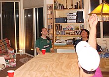 The game played seated, with a cup at each corner of the table Seated beer die game.jpg