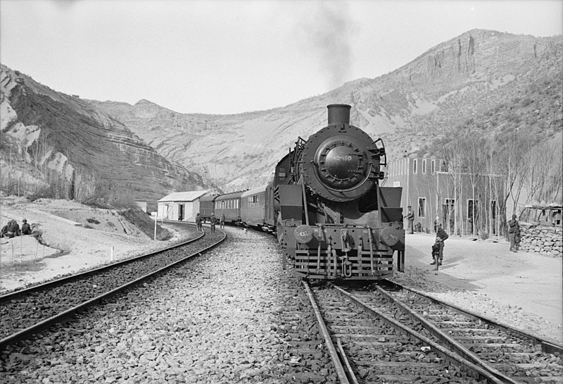 File:Somewhere in Iran. An American engine transporting allied aid for Russia, stopping at a station rimmed by mountains.jpeg