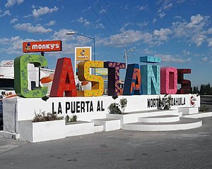 A sign depicting the city name of Castaños. Each letter is a different color. The black text under the letters reads as "la puerta al norte de coahuila", which roughly translates to "the door to the north of Coahuila"