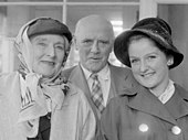 elderly white woman in headscarf; elderly white man, bald, clean shave; young white woman in hat, all looking face on to the camera