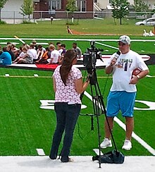 Kramer on camera with FOX News (KVRR) during a youth football clinic June 25, 2011, at Shanley High School in Fargo, ND. Tommy Kramer (2011).jpg