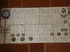 Таблетка, оформена от пет плочки с различни размери, сложно украсени с цветя и стилизиран шлем на английски полицай и оградени от жълти и сини цветя в стил ар нуво. На таблета пише „Алфред Смит, полицейски полицай, който беше убит при въздушна атака, докато спасяваше живота на жени и момичета на 13 юни 1917 г.“.