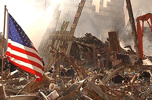 Rescue workers climb through rubble and smoke at the World Trade Center site, and an American flag flies at left