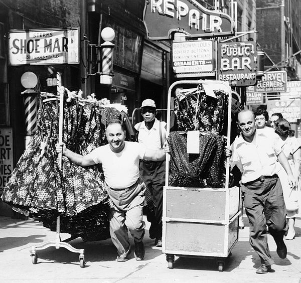 Men pulling carts of women's clothing in Garment District, New York, 1955