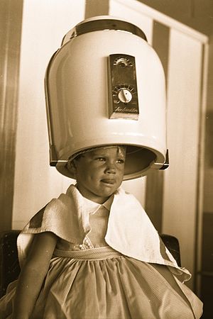Girl under beauty parlor hair dryer, 1958