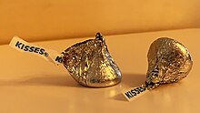 The "KISSES" paper strip plume and silver aluminum foil are the traditional packaging for the Hershey's Milk Chocolate Kiss Hershey's-Kiss-Wrapped-in-Foil-with-Plume-Sticking-Out.jpg