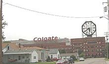 Foto con un gran edificio en la distancia con un logo de Colgate y un reloj.